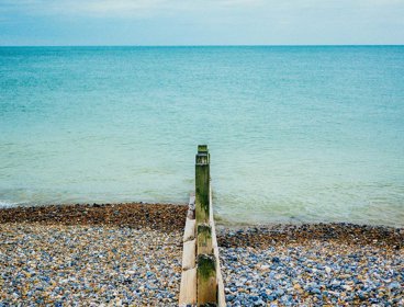 A pebble beach with a groyne, showing clearly the impact of longshore drift on pebble distribution.