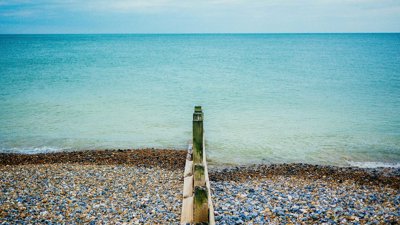 A pebble beach with a groyne, showing clearly the impact of longshore drift on pebble distribution.