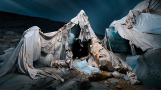 Torn thermally reflective blankets used as coverings draped around pieced of ice on a glacier.