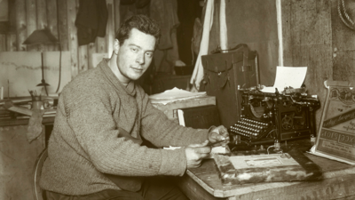 Black and white photograph of Apsley Cherry Garrard sat at a desk with a typewriter
