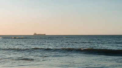 A container ship sailing on the calm sea horizon, captured at dawn.