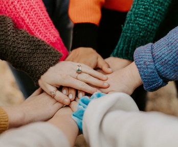 Individuals in a circle putting their hands together.
