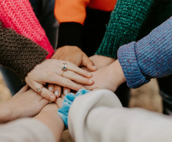 Individuals in a circle putting their hands together.