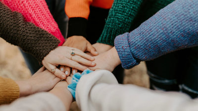 Individuals in a circle putting their hands together.