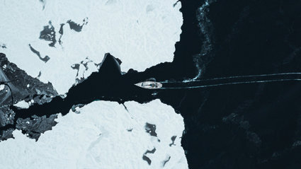 A ship crossing through two glaciers seen from far above.