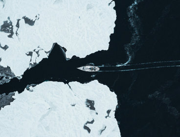 A ship crossing through two glaciers seen from far above.