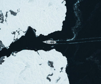 A ship crossing through two glaciers seen from far above.