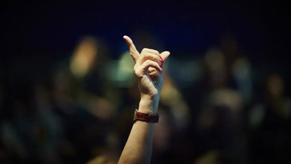A hand is raised in a lecture theatre to display the desire to ask a question.