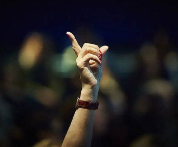 A hand is raised in a lecture theatre to display the desire to ask a question.
