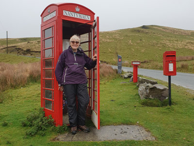 Heather standing in red telephone box in rural landscape