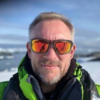 Jon Beardmore wearing reflective yellow/orange sunglasses, in a polar environment.