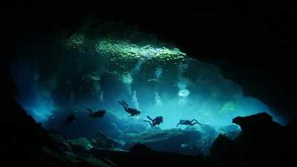 A group of four divers in an underwater cave.