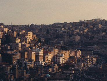 Sunlit hillside densely packed with multi-story buildings.