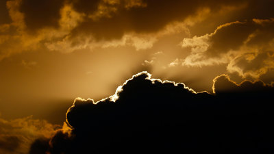 The sun is shining behind clouds, creating a golden effect in the sky.