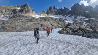 Group of people traversing a glacier and hiking a mountain.