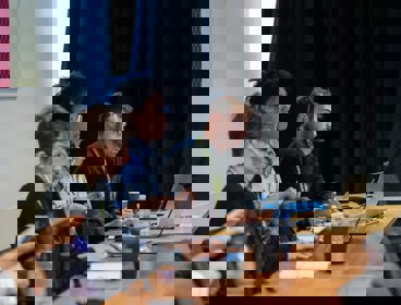 Three conference delegates seated and listening to a conference presentation