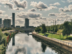 City Mill River in London within the Queen Elizabeth Park with skyscrapers in the background on an overcast day.