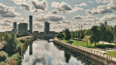 City Mill River in London within the Queen Elizabeth Park with skyscrapers in the background on an overcast day.