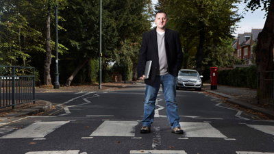 Ed Parsons standing on a crossing holding a laptop.