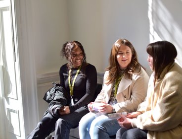 Three people sat down smiling and in conversation.