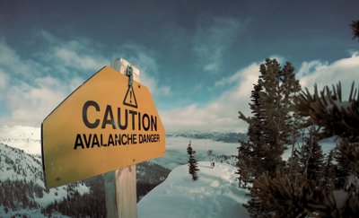 A yellow sign that reads 'Caution Avalanche danger'