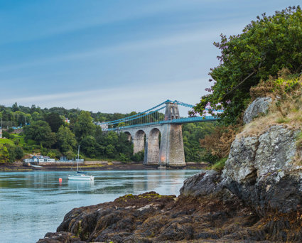 Blue bridge over water with rocks in the foreground