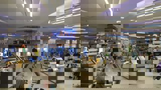 Manchester central library, showing self-service checkouts and tables with people sitting. There are also people walking around.