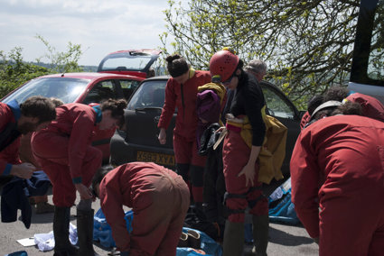 People wearing red caving gear and preparing for a descent