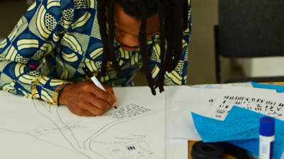A person sitting at a table writing on a paper drawing