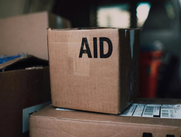 Cardboard boxes stacked on top of eachother, displaying the word 'Aid'.