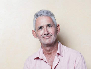 Headshot of Tim Spector wearing pink shirt against pale background.