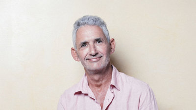 Headshot of Tim Spector wearing pink shirt against pale background.