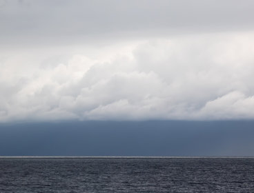 A seascape with white fluffy clouds over a grey sea
