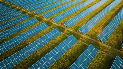 Vast solar panel farm on grass as seen from above.