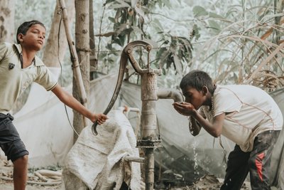 Indian boys at water pump, one is drinking