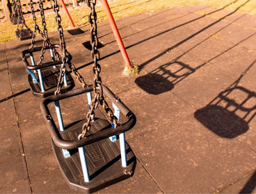 Four empty swings in playground park.
