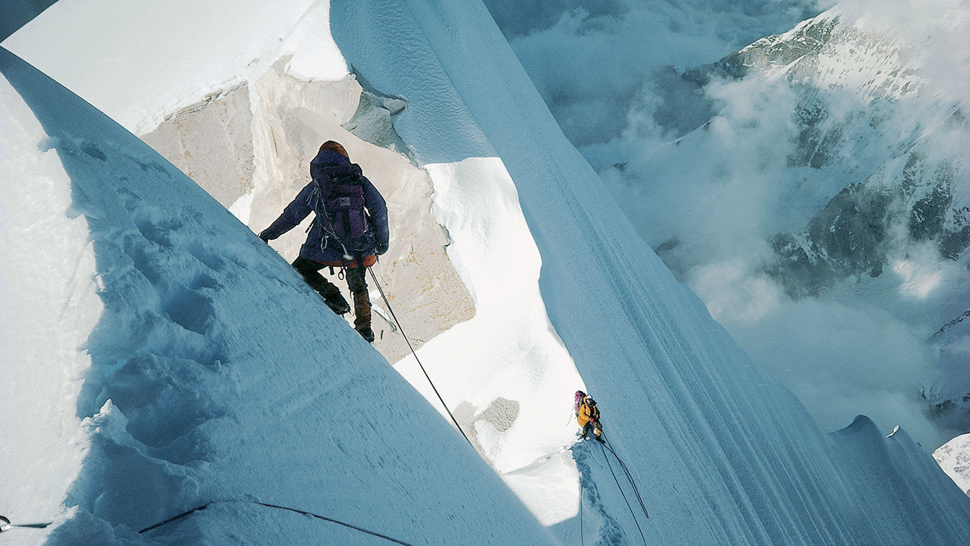 Two mountaineers ascenting a steep, snow- and ice-covered mountain.