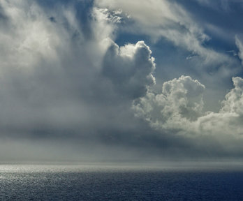 Moody grey clouds forming over the sea, light bouncing off the edges of the clouds.
