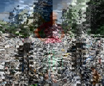 A person in traditional dress standing in a pile of plastic with hands on their hips.