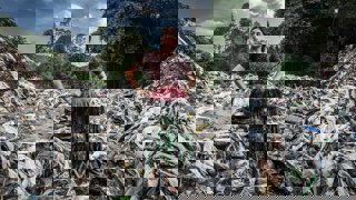 A person in traditional dress standing in a pile of plastic with hands on their hips.