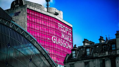 Industrial building with bright pink sign on outside.