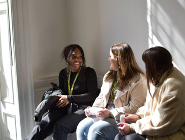 Three postgraduates chatting to each other at conference.