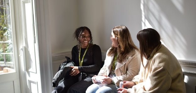Three postgraduates chatting to each other at conference.