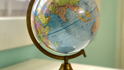 A globe sits on a white table next too a window. The background is blurred