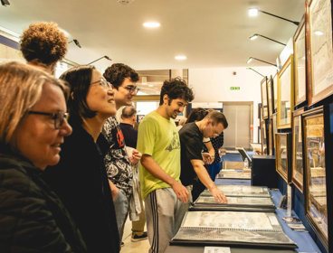 People at a map fair looking at maps disokated on tables.