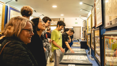 People at a map fair looking at maps disokated on tables.