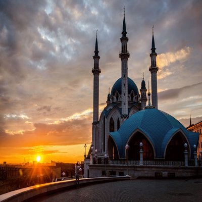 The sun is setting over ornate Russian buildings, which have arched windows, thin towers and turrets