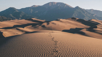 A trail of foot prints fade off into the expanse of the Kelso Dunes, United States.