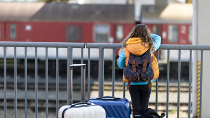 Young child with a backpack looking at a train.