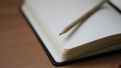 Close up of an open notebook with a pencil laying on top.